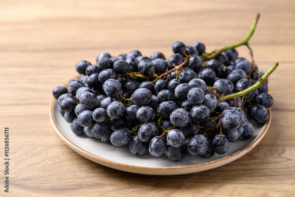 Black grapes on plate with wooden table, Seedless grapes Black grapes on plate with wooden table, Seedless grapes