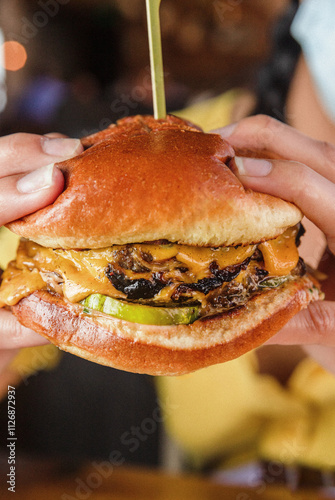 Person Holding Cheeseburger in a Restaurant