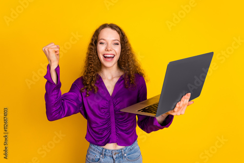 Photo portrait of attractive young woman hold netbook winning dressed stylish violet clothes isolated on yellow color background