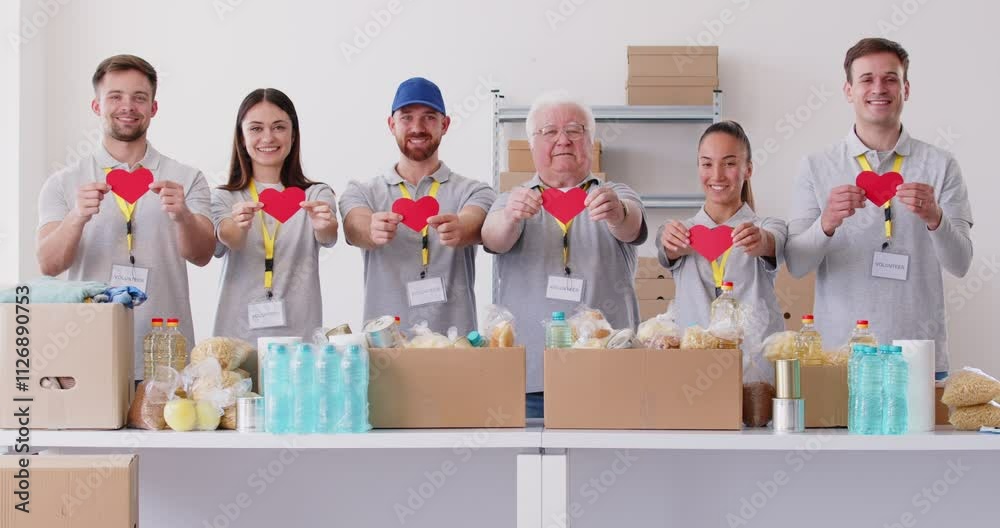 Portrait of a smiling volunteers holding red hearts in hands standing at charity center working in charitable foundation. Humanitarian aid and social help concept. 4k video. Slow motion video.