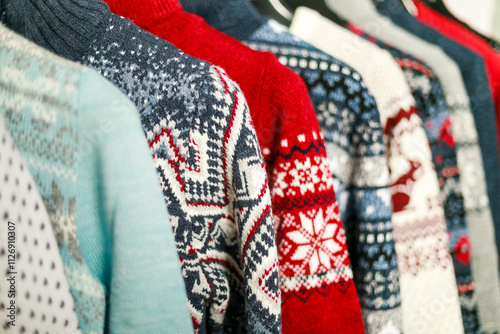 Assortment of winter knit sweaters with seasonal patterns displayed on a rack