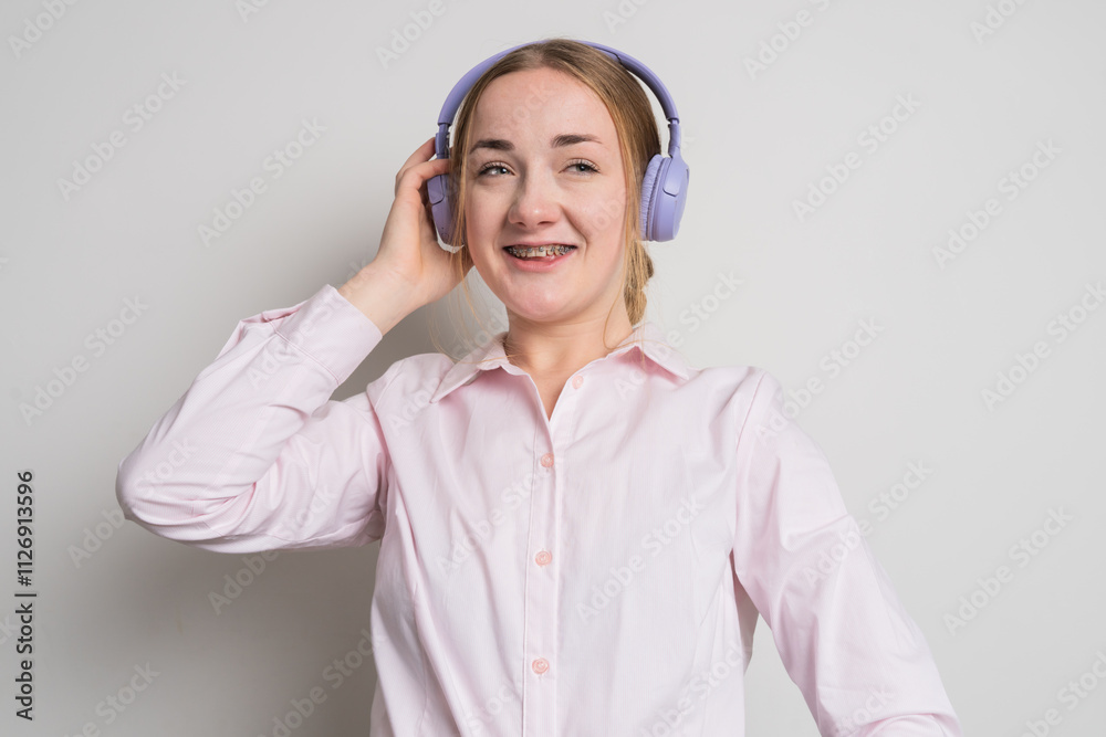 Modern woman smiling with braces on her teeth and listening to music in headphones Modern woman smiling with braces on her teeth and listening to music in headphones