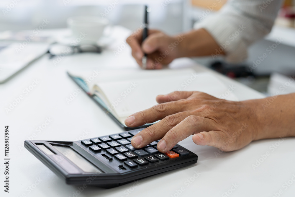 accountant reviews financial data using a calculator at desk in a busy office, ensuring accuracy in tax reporting and financial management. accountant reviews financial data using a calculator at desk in a busy office, ensuring accuracy in tax reporting and financial management.