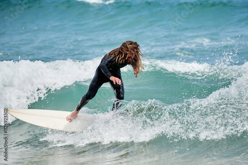 Long-haired surfer with board walking on beach