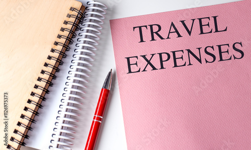  Travel expenses concept with pink folder, notebooks, and red pen on white background
