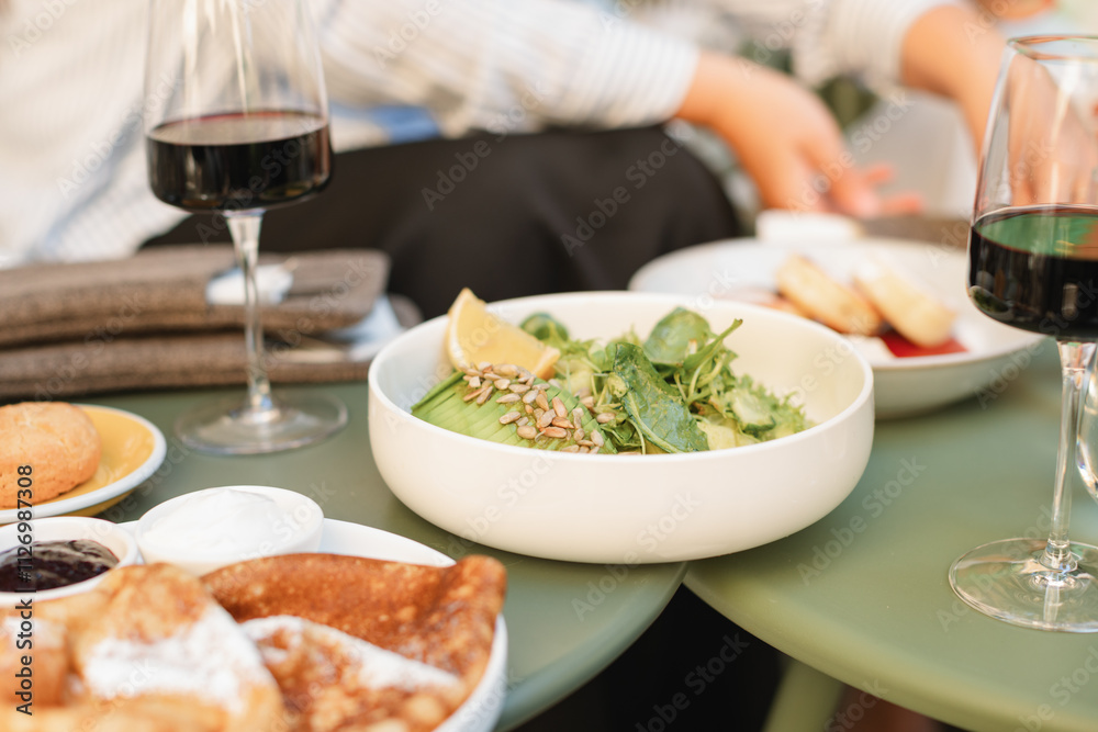 Close-up of an avocado, lettuce, cucumber and sunflower seed salad on a cafe table with bread and red wine Close-up of an avocado, lettuce, cucumber and sunflower seed salad on a cafe table with bread and red wine