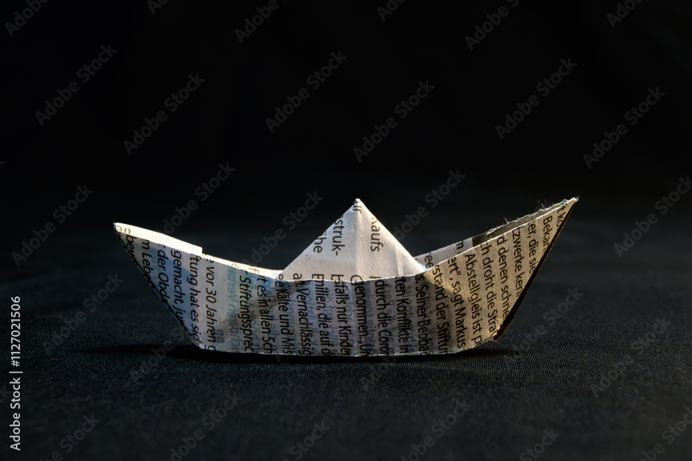 Obraz premium Simple Origami Boat Made From Newspaper On Dark Background