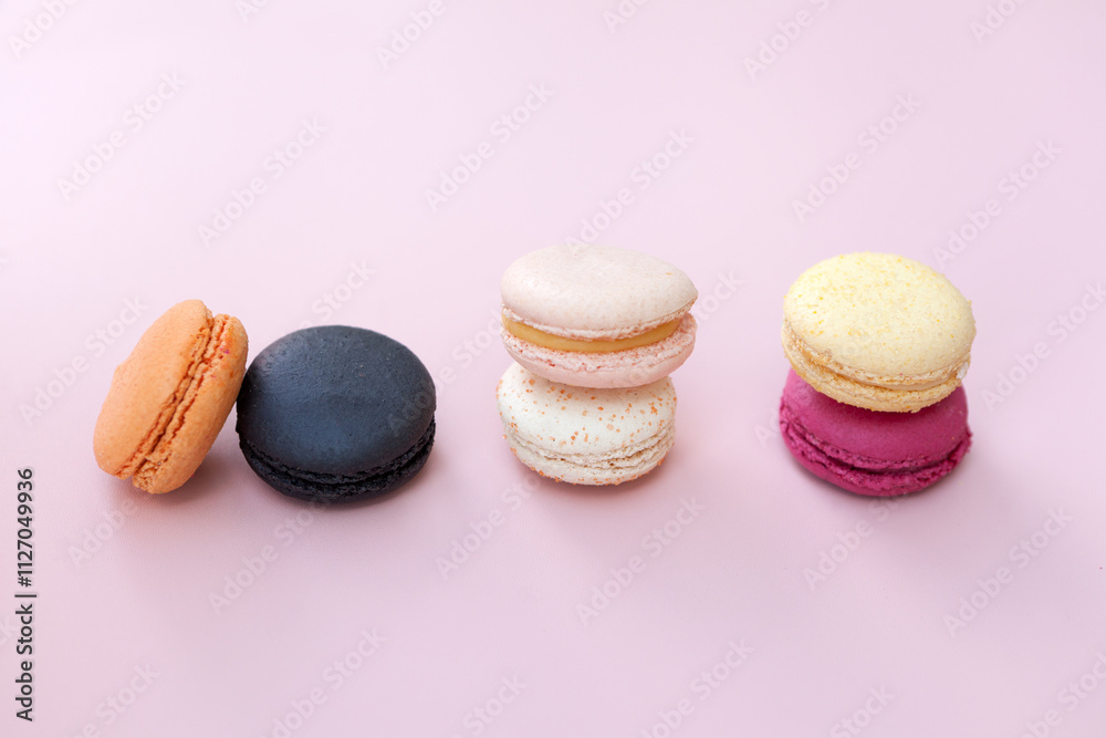 Fototapeta premium sweet meringue. Bright food photography of macroons, various macarons, from above on a vibrant pink background with crumbs and copyspace-French macaroon