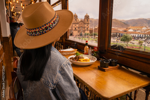 Latin tourist having lunch and looking at the Cusco square from the window photo