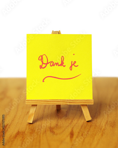 A yellow thank you note with the words 'Dank je,' meaning 'thank you' in Dutch, on a miniature easel.