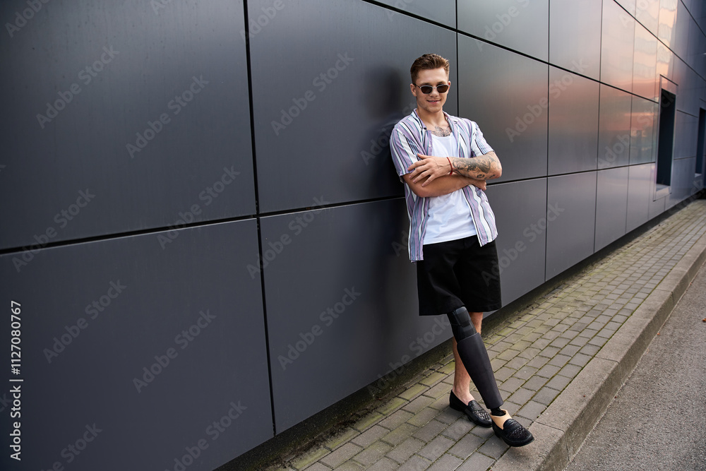 Young man with a prosthetic leg poses with confidence near a sleek urban building. Young man with a prosthetic leg poses with confidence near a sleek urban building.