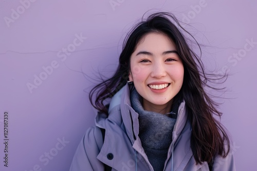 Portrait of a smiling asian woman in her 20s wearing a windproof softshell on soft purple background photo