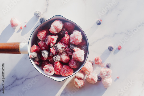 frozen mix berries in white enamel pot preparation to make mix berry jam. photo