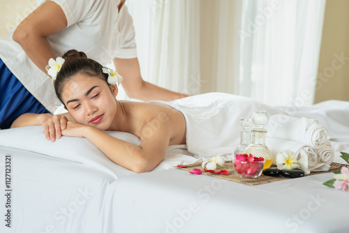 Beautiful Asian woman lying down on massage bed relaxing in spa salon