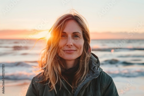 Portrait of a content woman in her 40s wearing a functional windbreaker in stunning sunset beach background