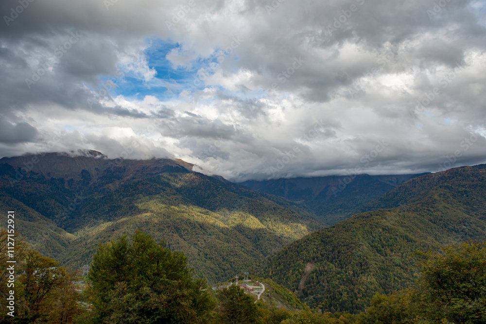 Cloudy evening at a picturesque mountain resort in autumn, heavy thunderclouds. Mountain peaks are shrouded in dark clouds. Early autumn, picturesque mountain ranges Cloudy evening at a picturesque mountain resort in autumn, heavy thunderclouds. Mountain peaks are shrouded in dark clouds. Early autumn, picturesque mountain ranges