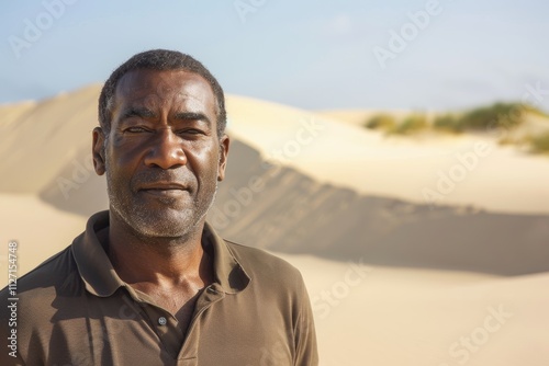 Portrait of a tender afro-american man in his 40s wearing a sporty polo shirt isolated on serene dune landscape background