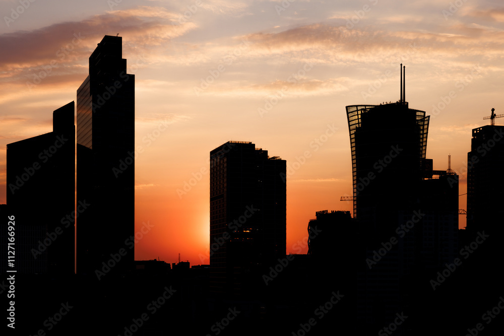Naklejka premium A skyline skyscrapers silhouette against a colorful sunset.