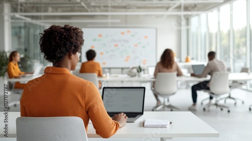 Professional woman attending a modern business meeting with laptop in an open office, collaborating with colleagues in a bright atmosphere, focused on the presentation