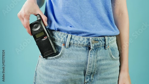 80s 90s retro vintage cell phone being used by a young adult woman, taking old mobile phone with antenna from jeans pocket. photo