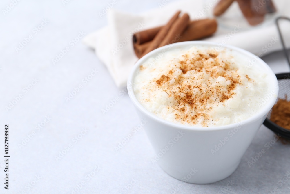 Delicious rice pudding with cinnamon on light table, closeup. Space for text Delicious rice pudding with cinnamon on light table, closeup. Space for text