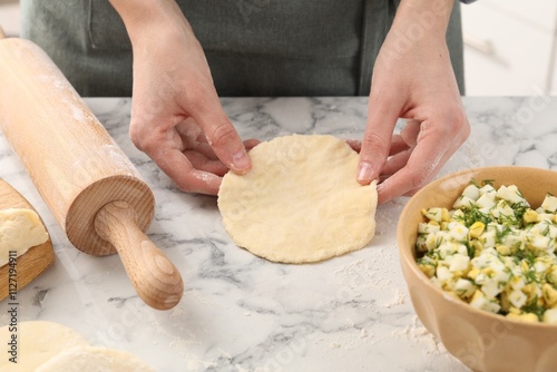 Woman making pirozhki (stuffed pastry pies) at white marble table indoors, closeup photo