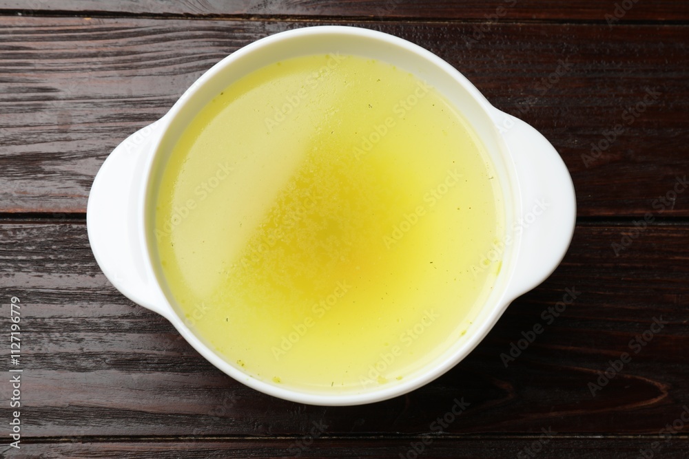 Tasty chicken bouillon in bowl on wooden table, top view Tasty chicken bouillon in bowl on wooden table, top view