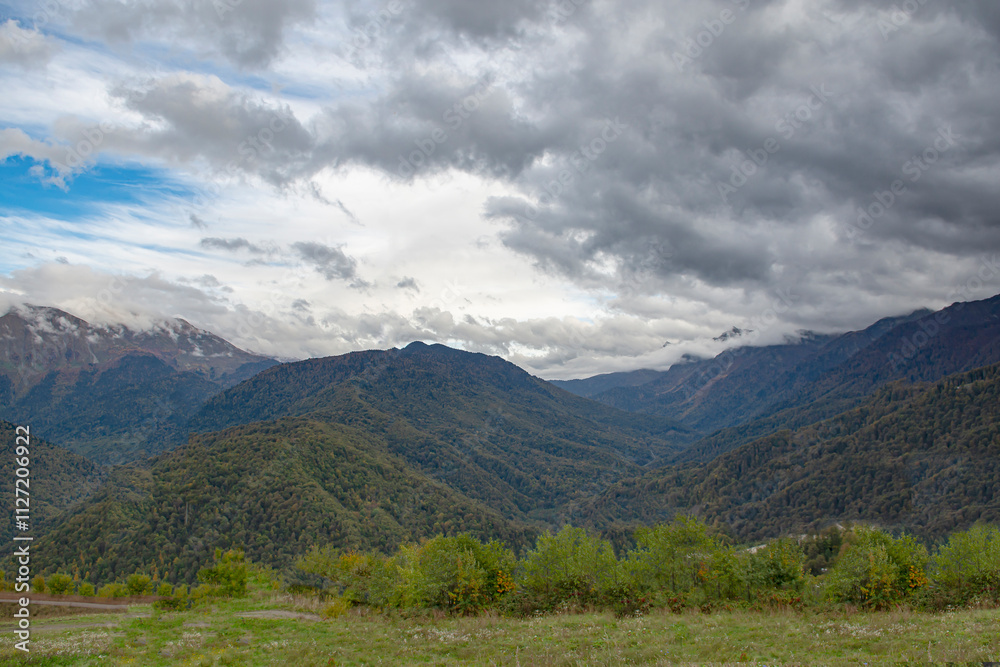 Cloudy evening at a picturesque mountain resort in autumn, heavy thunderclouds. Mountain peaks are shrouded in dark clouds. Early autumn, picturesque mountain ranges Cloudy evening at a picturesque mountain resort in autumn, heavy thunderclouds. Mountain peaks are shrouded in dark clouds. Early autumn, picturesque mountain ranges
