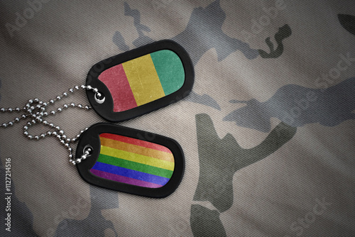 army blank, dog tag with rainbow gay pride flag and guinea on the khaki texture background. military concept.