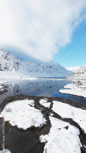 Road surrounding lake in snowy mountain range in Norway