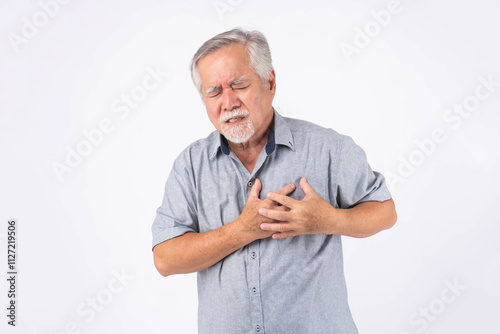 Senior Asian man experiencing chest pain, showing signs of a heart attack or cardiovascular problem, wearing a casual gray shirt and standing against , isolated on white background