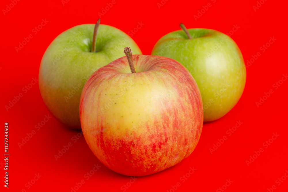 Three red apples and two green ones on a red background. Three red apples and two green ones on a red background.