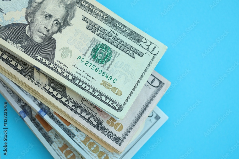 Big amount of hundred, fifty and twenty dollar bills in thick stack lies on bright blue color paper background Big amount of hundred, fifty and twenty dollar bills in thick stack lies on bright blue color paper background