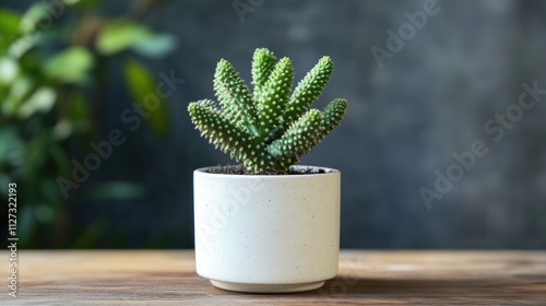 Cactus plant in a minimalist white pot on wooden table with blurred greenery background. Perfect for home decor or nature themes. photo