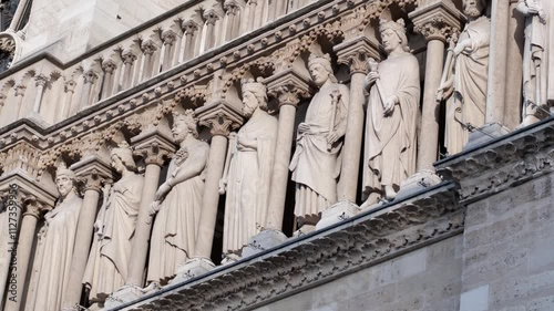 Intricate stone carvings of saints on the facade of Notre Dame Cathedral in Paris, showcasing Gothic architecture and religious art