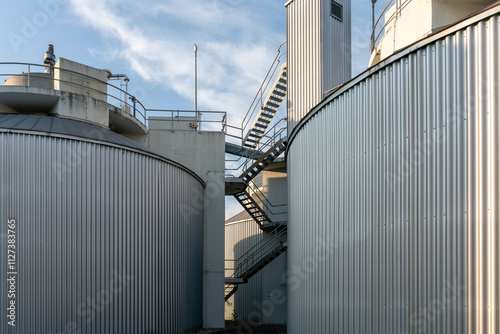 Biogas production facility closeup. Stairways to get to the top of the equipment. Blue sky.