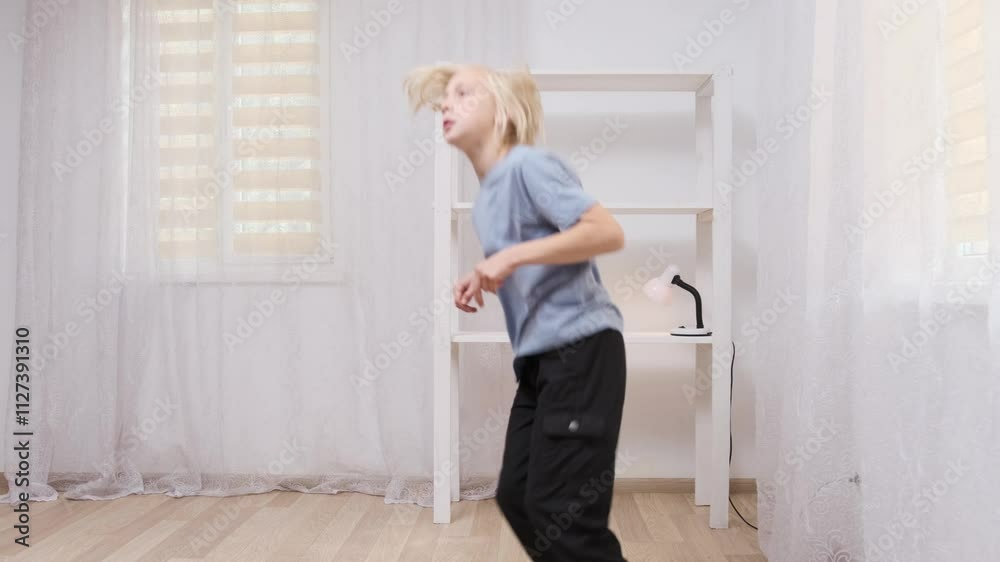 Young boy practicing modern dance moves in a bright room, showcasing energetic movements in captivating slow motion Young boy practicing modern dance moves in a bright room, showcasing energetic movements in captivating slow motion