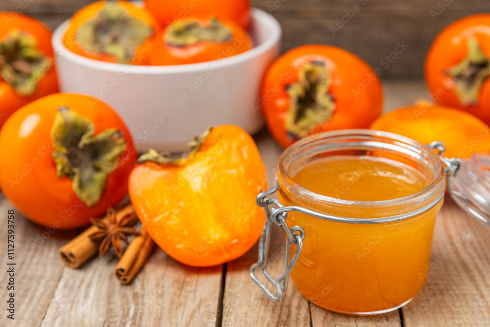 Persimmon jam with slices of ripe persimmon on wooden textured table. Delicious persimmon jam. Marmalade. Healthy sweets. Vegan. Close-up. Space for text. Copy space. Persimmon jam with slices of ripe persimmon on wooden textured table. Delicious persimmon jam. Marmalade. Healthy sweets. Vegan. Close-up. Space for text. Copy space.