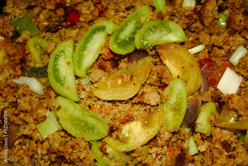 The savory and slightly spicy oncom is served with fresh green tomato slices arranged in a circle on top.