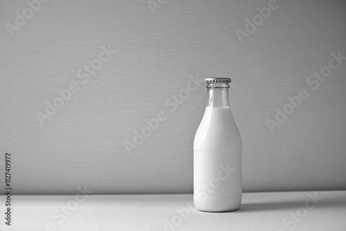 Full glass bottle of milk with blank label standing on white table against gray background