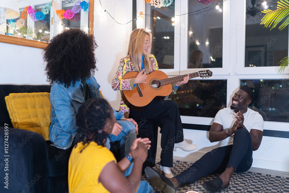 Fototapeta premium Friends playing acoustic guitar and clapping at home party