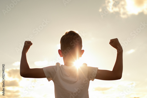 Silhouette of strong healthy active confident boy child flexing muscles feeling like a winner, child growth strength determination victory