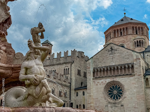 Fountain with statue of Neptune on historic square Piazza Duomo in city of Trento, Trentino Alto Adige, Italy. Majestic Trento Cathedral stands in background. Travel destination and tourist attraction