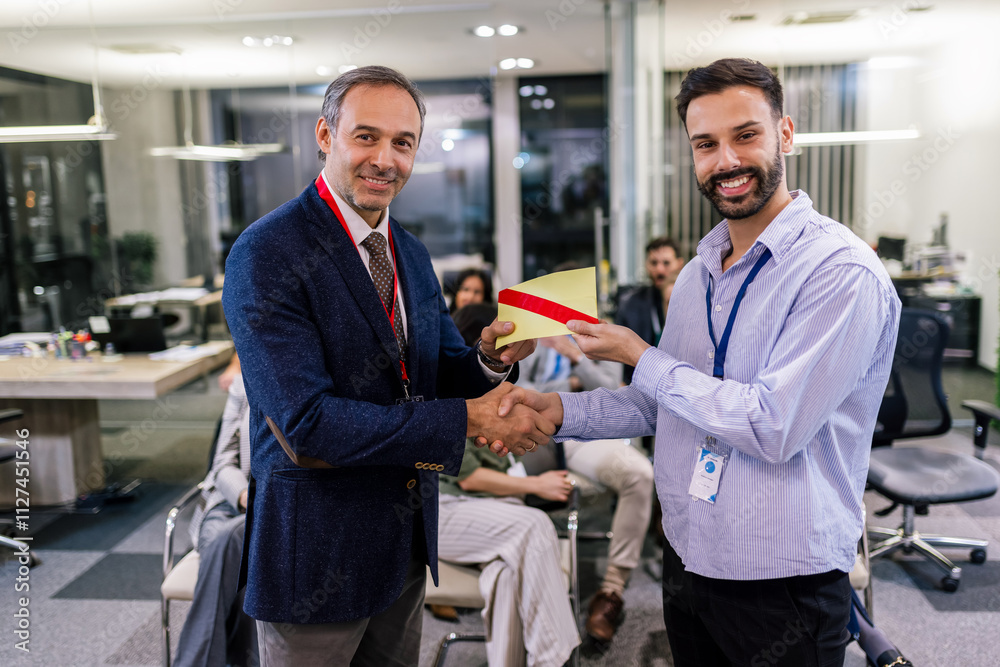 Fototapeta premium Front view of businessman receiving award from businessman in front of business professionals applauding at business seminar in office building