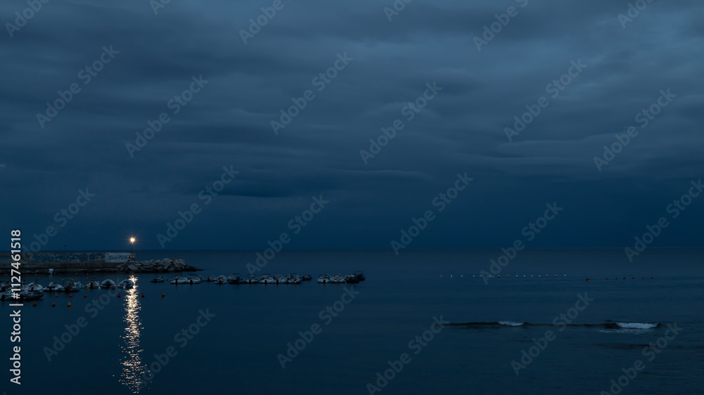 Blue evening on the coast next to the harbor and boats. Sardinia Blue evening on the coast next to the harbor and boats. Sardinia