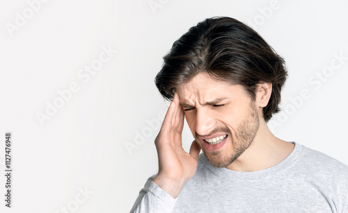 Young beautiful man suffering from headache. Puts hand on head