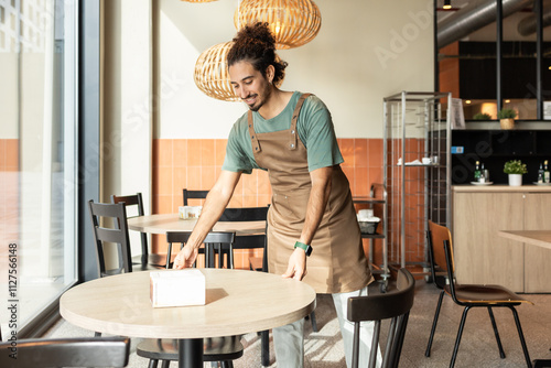 Cafe Employee Setting Up Tables in a Cozy Coffee Shop