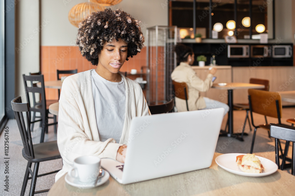 Young professional working on a laptop in a cozy cafe setting Young professional working on a laptop in a cozy cafe setting