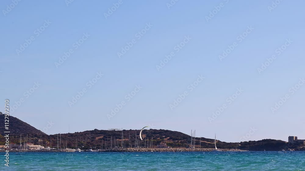 Vibrant kite surfing in Campulongu Bay, Sardinia, framed by yachts, marina views, and the Capo Carbonara peninsula. Vibrant kite surfing in Campulongu Bay, Sardinia, framed by yachts, marina views, and the Capo Carbonara peninsula.