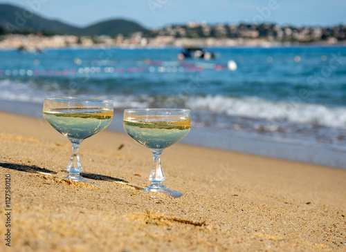 Summer time on French Riviera, two coupe glasses of champagne cremant sparkling wine on Pampelonne sandy beach near Saint-Tropez in sunny day, Var, vacation in France photo